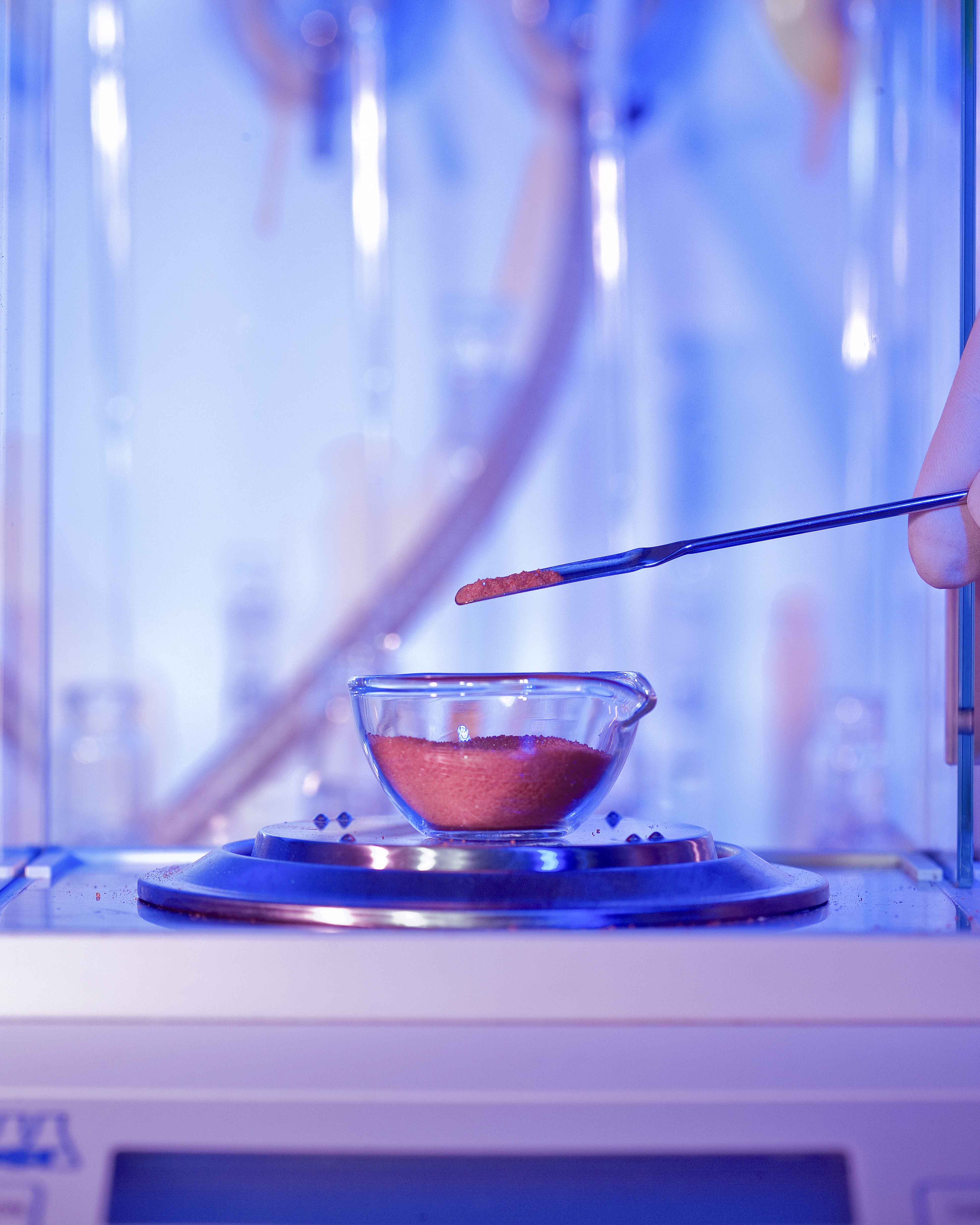 Scientist's hand weighing a powdered substance in a laboratory