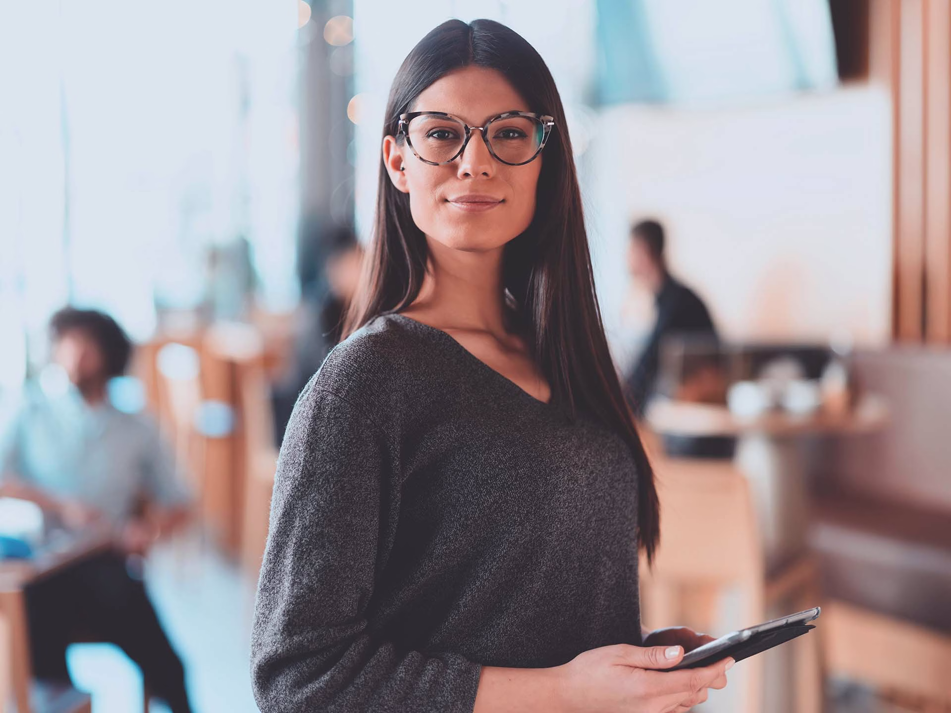 A woman holding a tablet looking at the camera